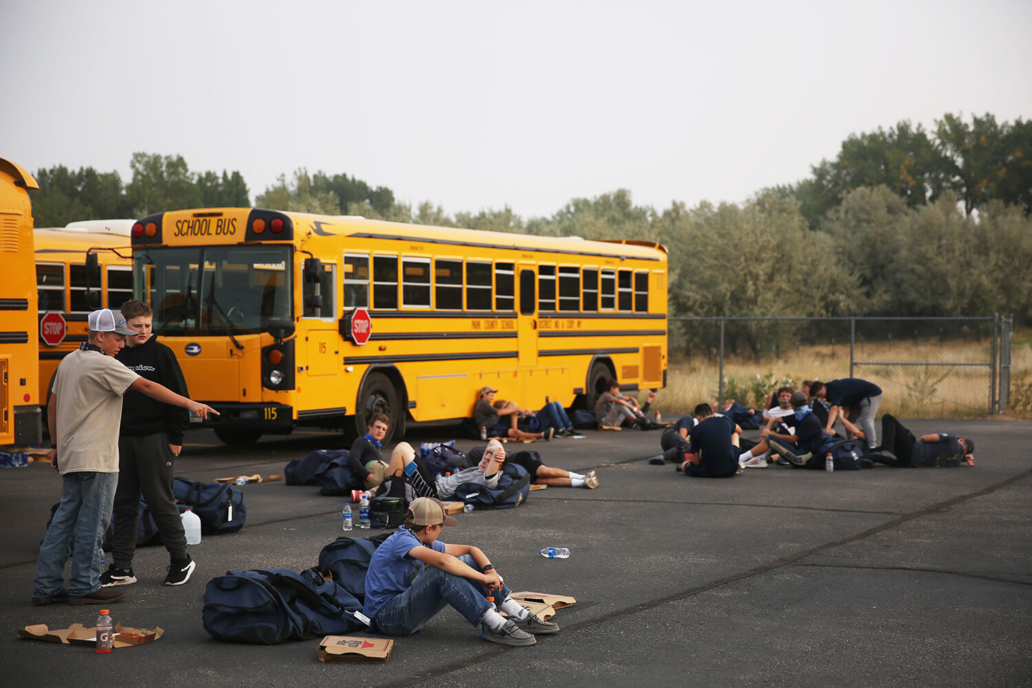 Cody High School’s JV team sprawls out in the parking lot near their buses